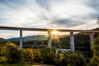 Das Foto zeigt die Siegtalbrücke im Sonnenuntergang. Die Sonne scheint unter der Brücke durch. Das Foto wurde auf einer Wiese oberhalb des Eiserfelder Nachtigallwegs aufgenommen